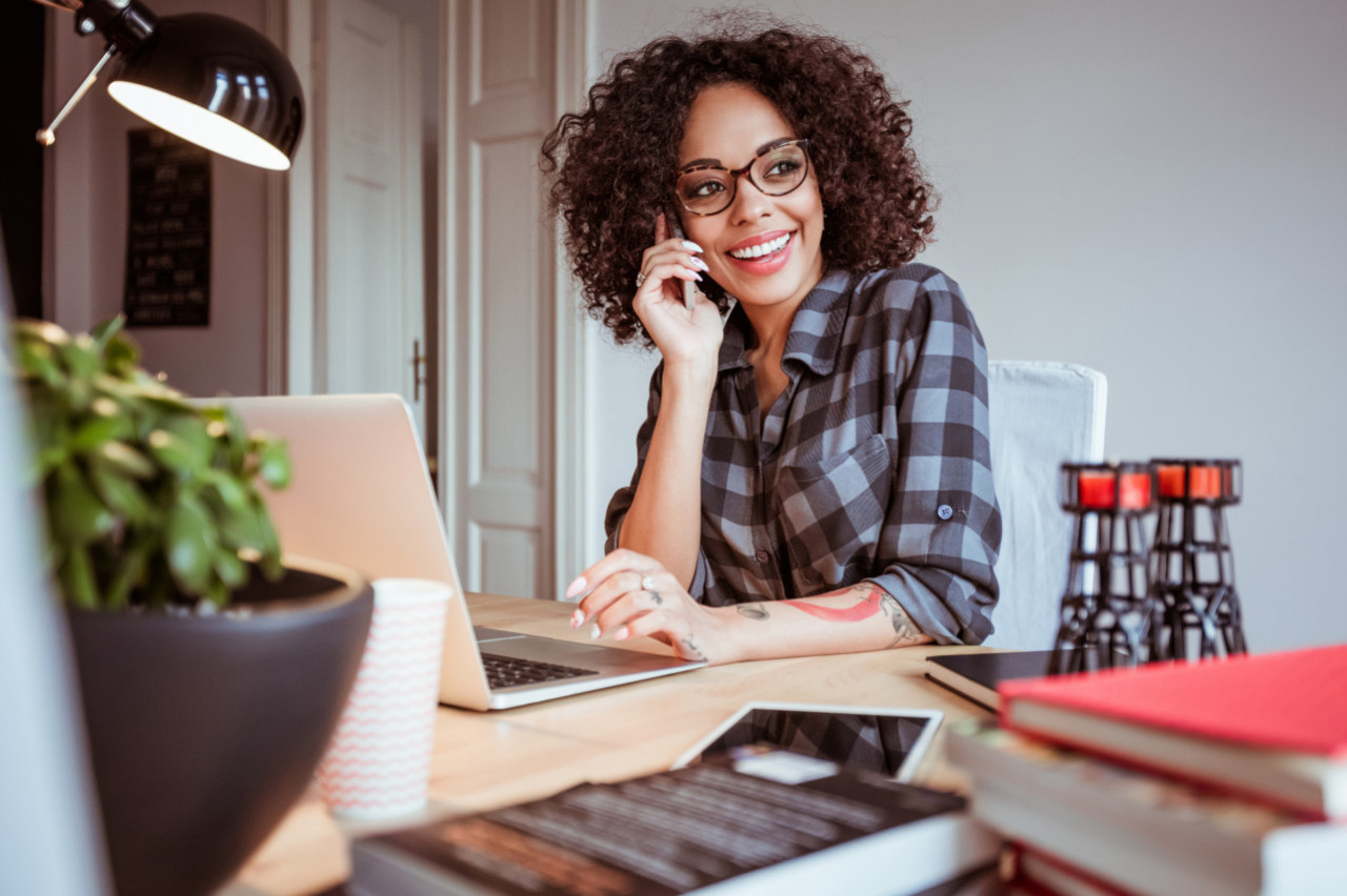 A woman speaking on the phone with a smile on her face.