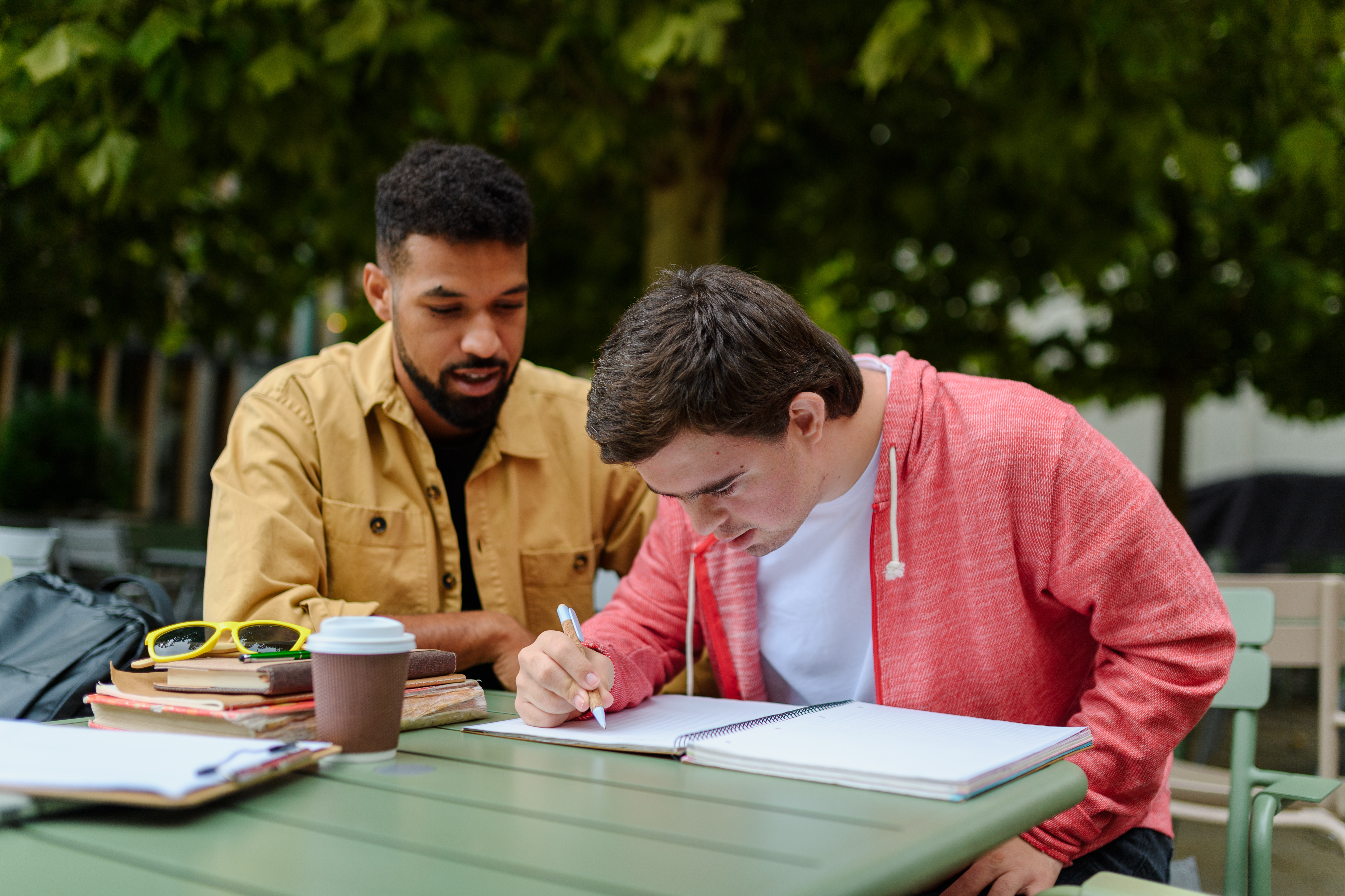 An adult helps an exceptional needs student in an outdoor setting.
