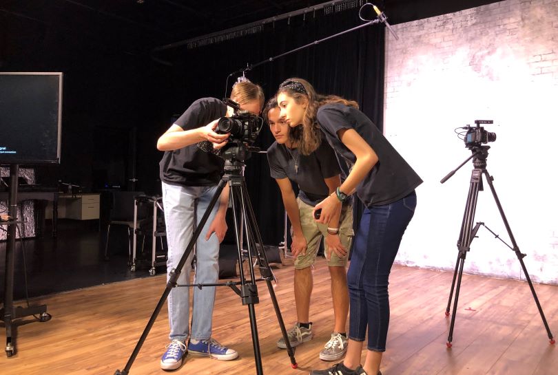 Two students using film equipment on location at an event.