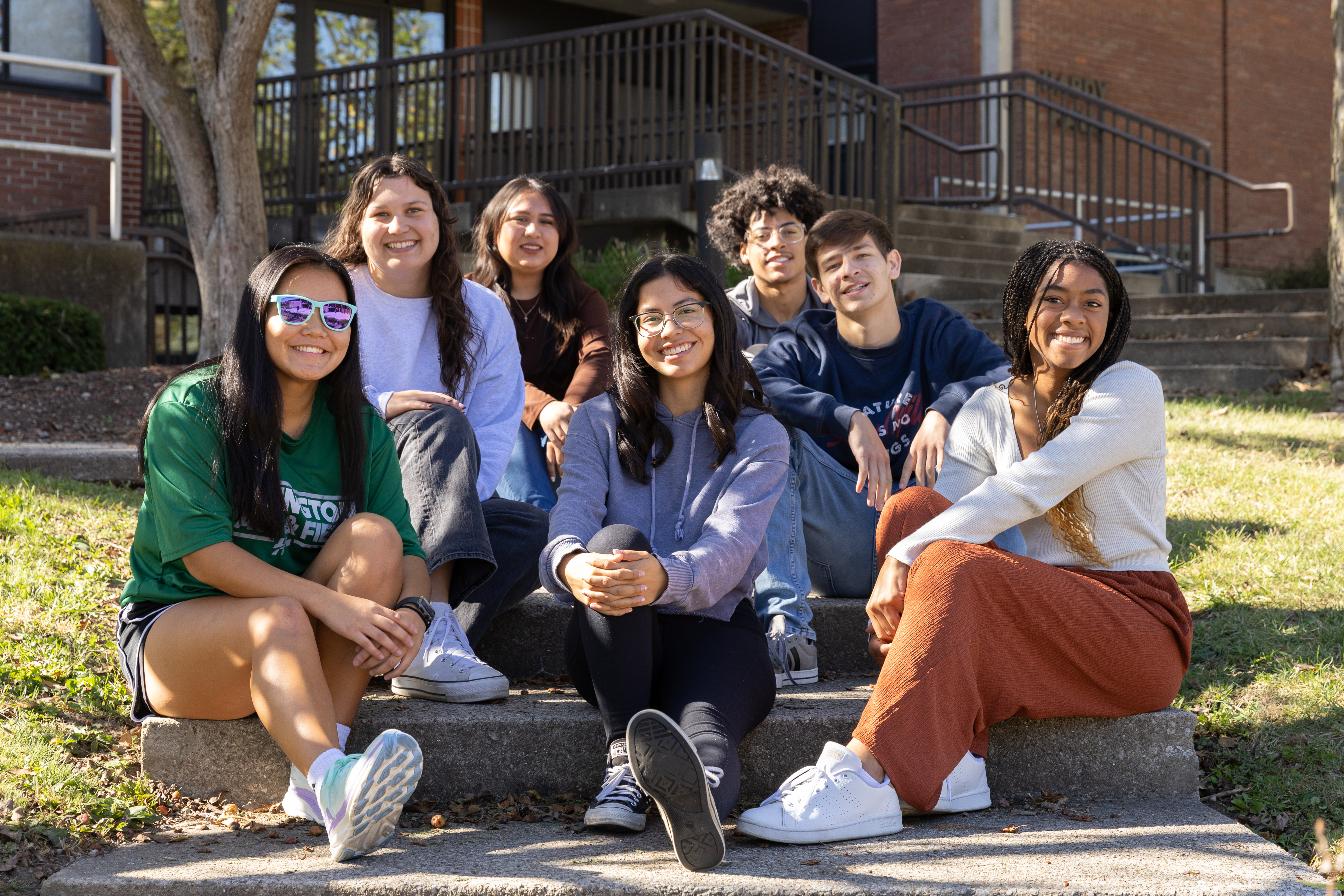 A group of students sits on the steps in front of Hardy Hall.