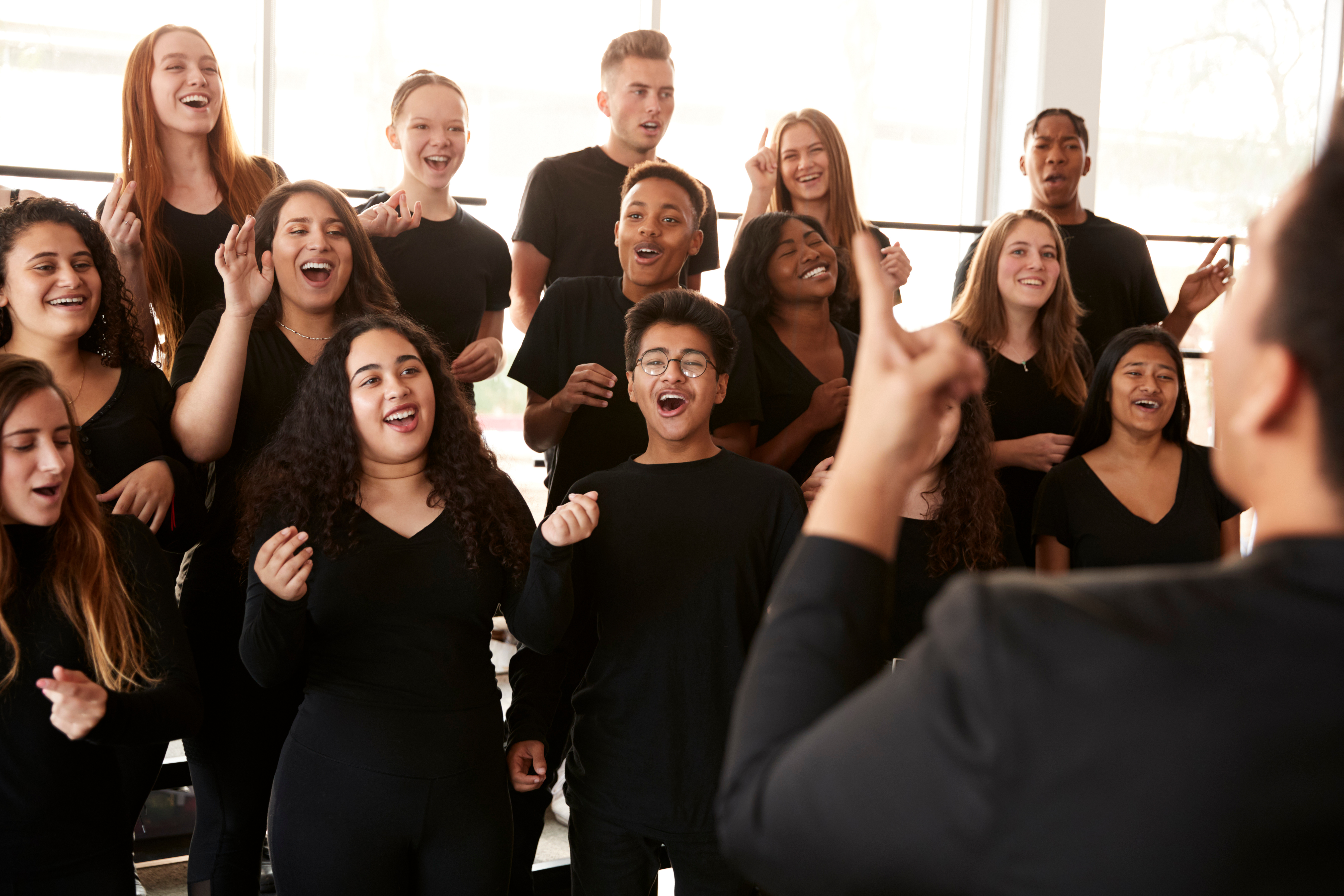 A group of students dressed in black sing together as a choir.
